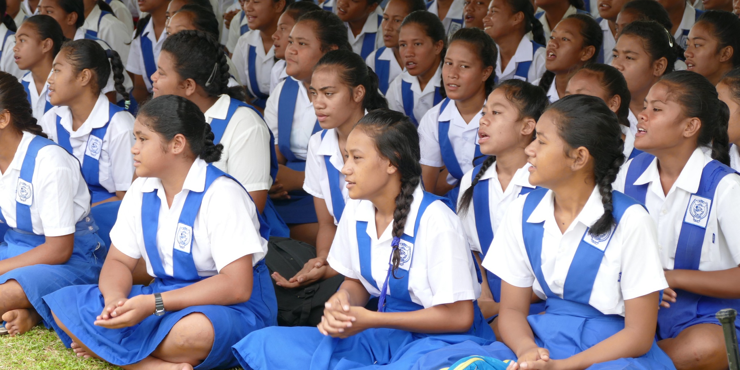 Students sit on the grass during the opening ceremony of the Safata College’s newly constructed multistory classroom block in Samoa – February 2018. Credit: US Embassy In New Zealand/Flickr